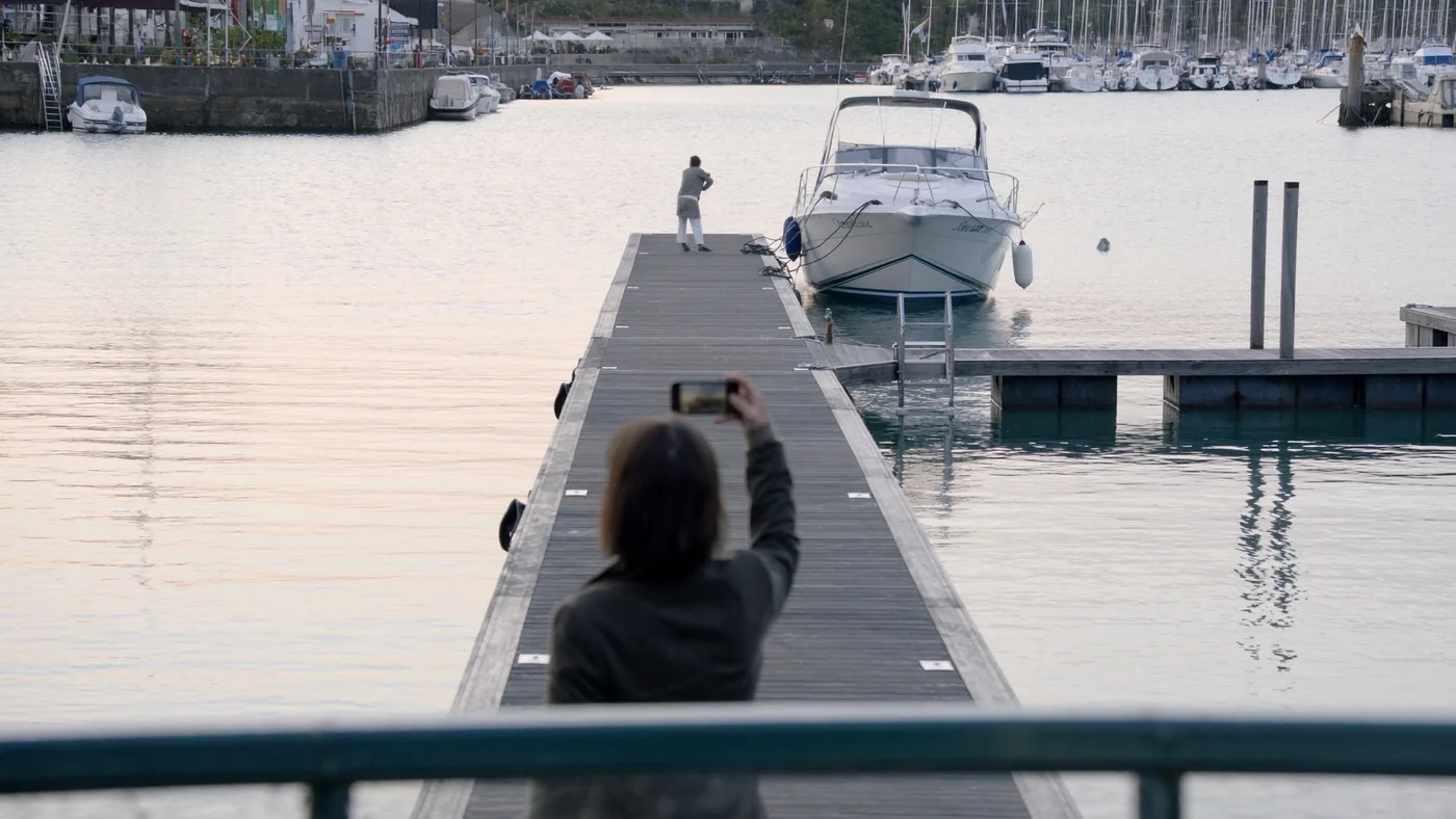 Persona sul pontile che fotografa con lo smartphone la propria barca ormeggiata